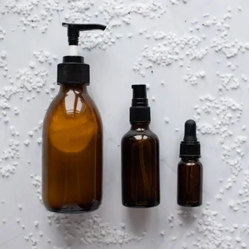 Three unlabelled skincare bottles on a pale surface