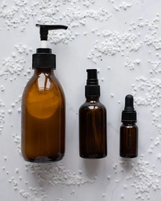 Three unlabelled skincare bottles on a pale surface