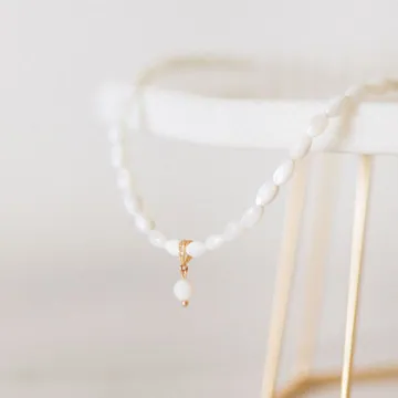 White beaded necklace on a simple display stand