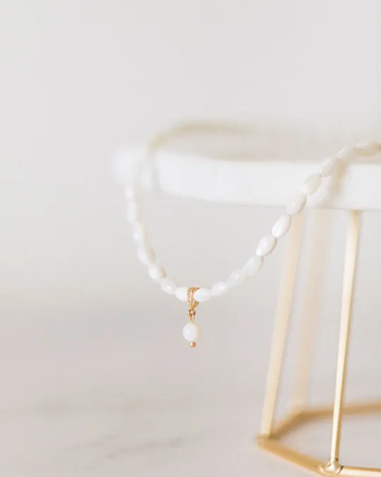White beaded necklace on a simple display stand