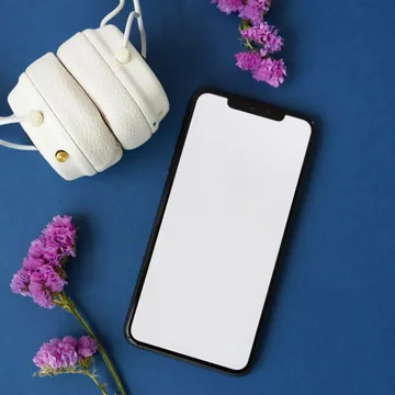 White headphones and a smartphone on a blue surface