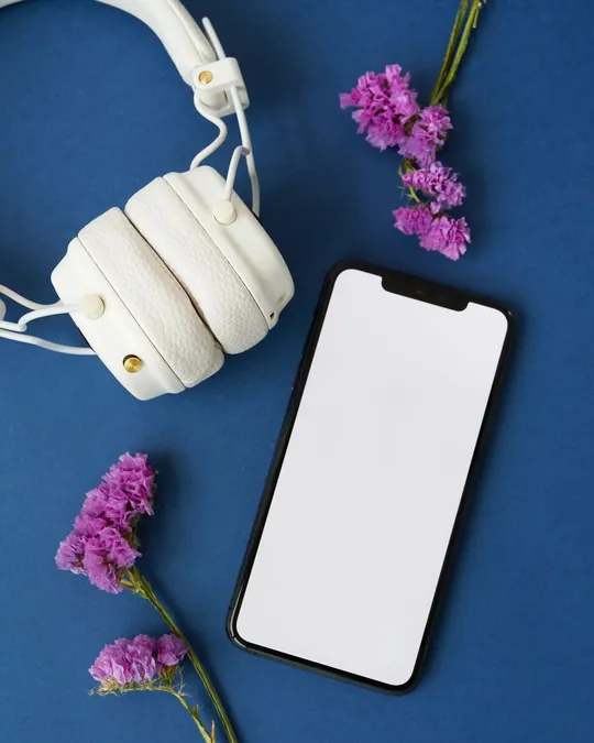 White headphones and a smartphone on a blue surface